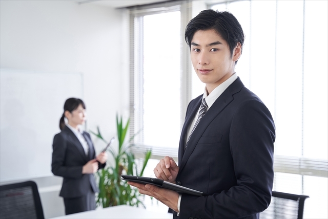 オフィスで笑顔で迎える日本人ビジネスマン