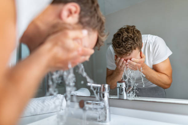 鏡の前で顔を洗う男性